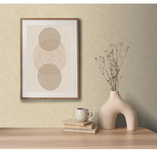 Decoratieve scène met een ingelijst abstract kunstwerk, een vaas met bloemen, boeken en een kopje op een tafel.