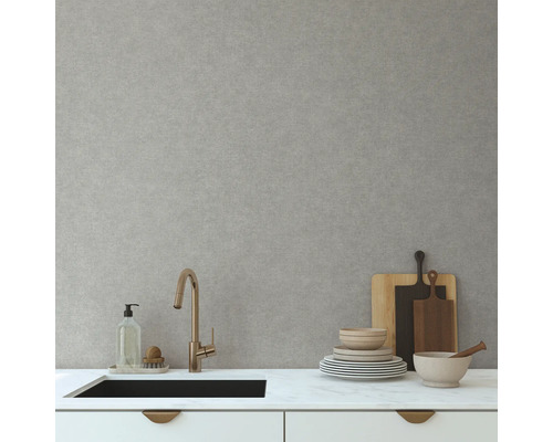 Keukenscène met gootsteen, kraan, servies en snijplanken tegen een lichtgrijze muur