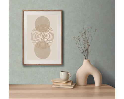 Decoratieve afbeelding met geometrische vormen in een houten lijst, samen met een vaas met takken, een kop en boeken op een tafel.