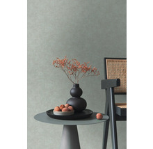 Decoratieve interieurscène met een tafeltje, een vaas met bloemen en een stoel tegen een gestructureerde wand.