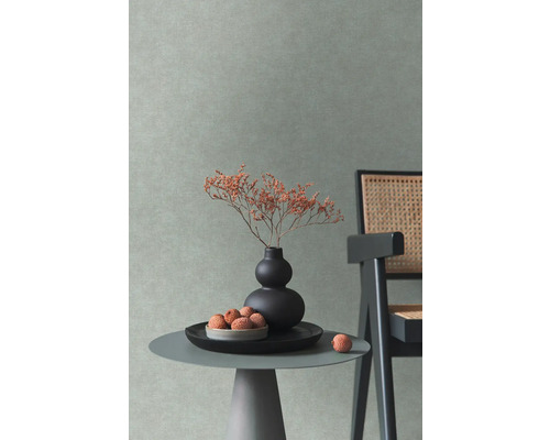Decoratieve interieurscène met een tafeltje, een vaas met bloemen en een stoel tegen een gestructureerde wand.