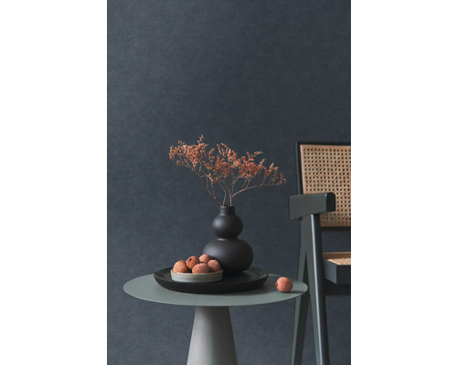 Decoratief stilleven met droogbloemen in vaas, fruitschaal en stoel op een bijzettafel tegen een donkere wand