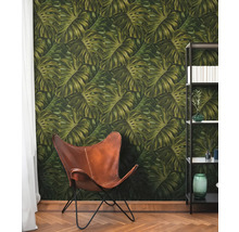 Kamer met behang met Monstera-bladmotief, lederen stoel en boekenkast