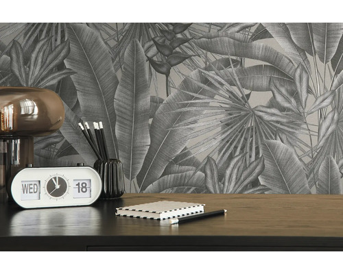 Close-up van een bureau met tropisch bladerbehang, een lamp, een kalender, pennen en een notitieboekje