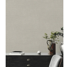 Close-up van een muur met een beige textielbehang boven een dressoir.