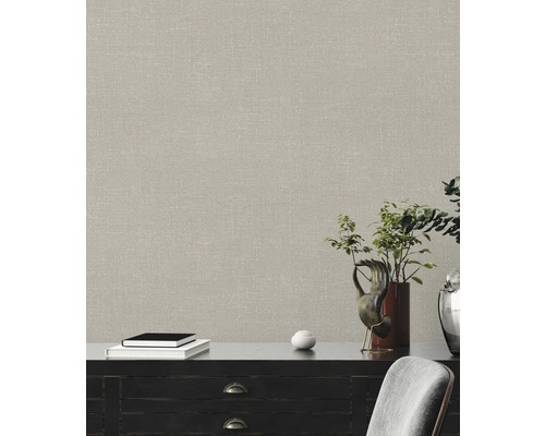 Close-up van een muur met een beige textielbehang boven een dressoir.