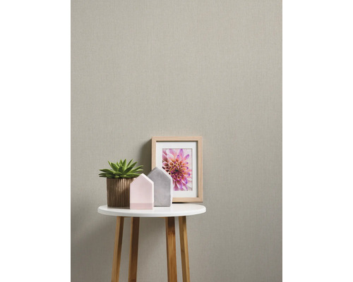 Close-up van een beige vliesbehang met tafel, potplant en fotolijst