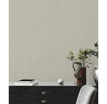 Close-up van een gestructureerd behang in een kamer met dressoir, boeken en plantdecoratie