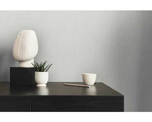 Close-up van een gestructureerd behang met minimalistische decoratie op een donkere houten commode.