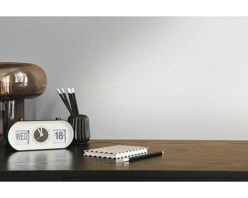 Decoratieve kamer met klok, pennen, notitieblok en lamp op een donkerhouten tafel voor een effen muur.