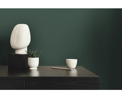 Decoratieve scène met sculptuur, plant, kopje en potlood op een donkere tafel voor een groene wand