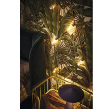 Decoratieve slaapkamer met behang met plantenmotief, lichtsnoer en nachtkastje.