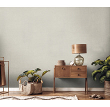 Scene met een houten commode, een lamp, kamerplanten en een gestructureerd behang