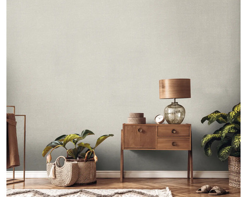 Scene met een houten commode, een lamp, kamerplanten en een gestructureerd behang