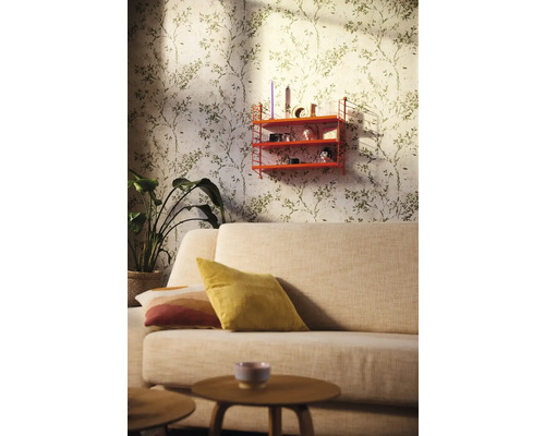 Woonkamer met bank, houten tafel, potplant, wandrek en behang met bladmotief