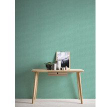Lichte kamer met effen behang, tafel, plant en decoratieve artikelen.