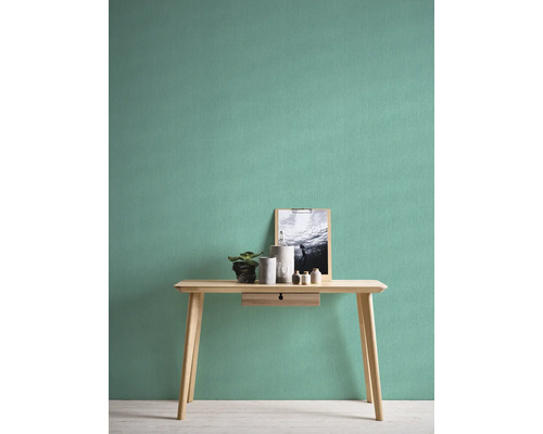 Lichte kamer met effen behang, tafel, plant en decoratieve artikelen.