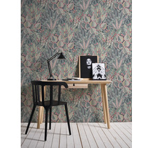 Een kamer met een bureau, een stoel en behang met een plantenpatroon.