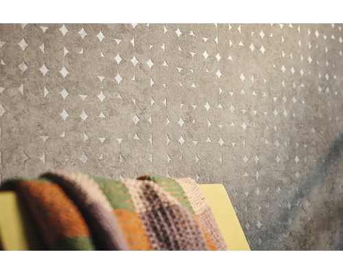 Close-up van een grijs vliesbehang met cirkelvormig patroon en uitsparingen