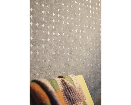 Grijs behang met cirkelpatroon en steruitsparingen aan een muur.