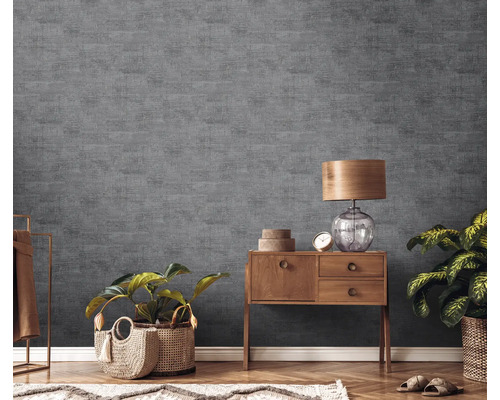 Woonkamer met grijs structuurbehang, houten dressoir, tafellamp en kamerplanten.