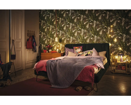 Slaapkamer met bed, nachtkastje en behang met print