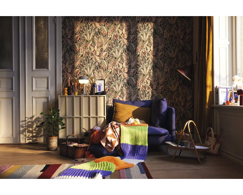 Woonkamer met gedessineerd behang, blauwe fauteuil en gebreide deken