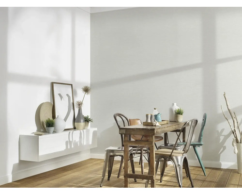 Lichte eetkamer met houten tafel, stoelen en witte wandplank met decoratie