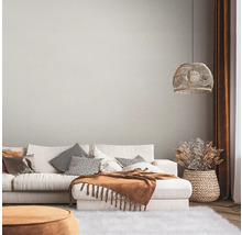 Woonkamer met bank, kussens, deken, lamp en decoratie in een lichte, gezellige stijl.