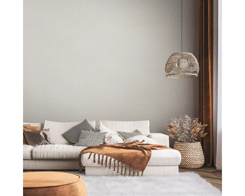 Woonkamer met bank, kussens, deken, lamp en decoratie in een lichte, gezellige stijl.