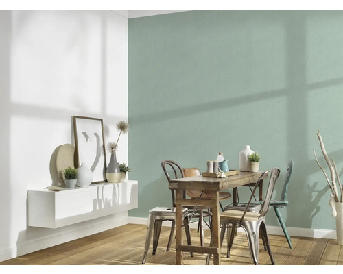 Eetkamer met houten tafel en stoelen voor een mintgroene muur