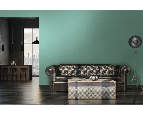 Woonkamer met leren bank, salontafel en staande lamp voor een muur met groen behang