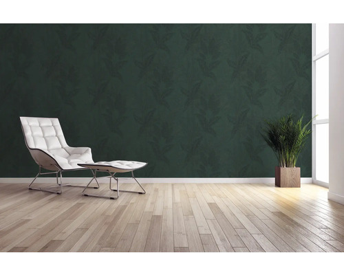 Woonkamer met groen bladbehang, fauteuil, voetenbank, potplant en houten vloer