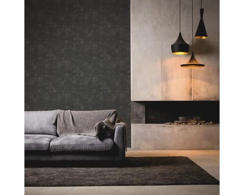 Woonkamer met grijze bank, deken, donker behang, open haard en drie hanglampen