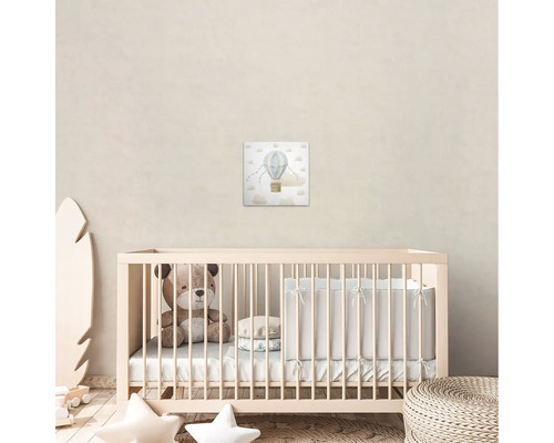 Kinderkamer met canvas schilderij van een luchtballon boven een wieg.