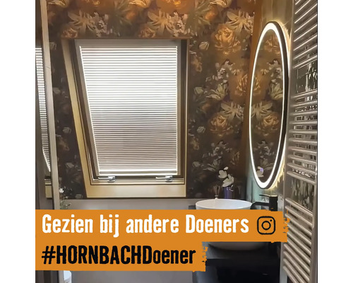 Badkamer met dakraam, jaloezie, wastafel en verlichte spiegel.