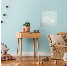 Kinderkamer met houten bijzettafel, regenboogafbeelding, rotan stoel en decoraties