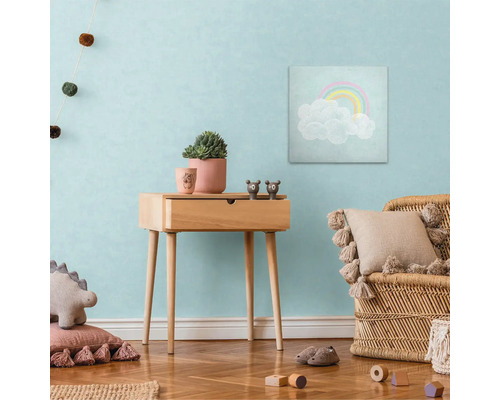 Kinderkamer met houten bijzettafel, regenboogafbeelding, rotan stoel en decoraties