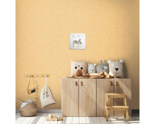 Kinderkamer met houten meubels, decoratieve kussens, kruk en een zebraprint met de tekst Be Cute.