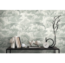 Interieurscène met wolkenbehang, boeken, decoraties en een klok op een zwarte tafel.
