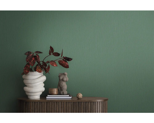 Decoratieve interieurscène met plant in sculpturale vaas, vrouwenbuste en twee boeken op een bruine kast tegen een groene achtergrond