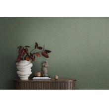 Close-up van een groen structuurbehang als achtergrond voor een interieur met plant, decoratie en meubelstuk