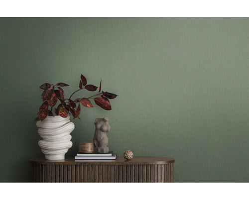 Close-up van een groen structuurbehang als achtergrond voor een interieur met plant, decoratie en meubelstuk