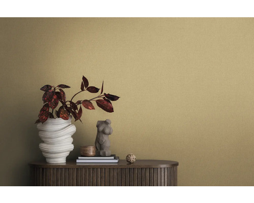 Close-up van een kamer met gestructureerd behang, een dressoir, een bloemenvaas en decoratieve elementen.