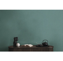 Detailopname van een groen structuurbehang boven een tafel met decoraties.