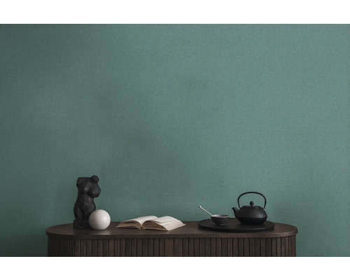 Detailopname van een groen structuurbehang boven een tafel met decoraties.