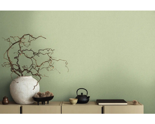 Decoratieve scène met vaas, takken, theepot en andere decoratieve elementen op een dressoir voor een wand