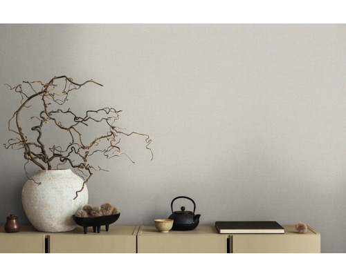 Close-up van een gedecoreerde ladekast met vaas, takken en theepot voor een beige wandbehang.