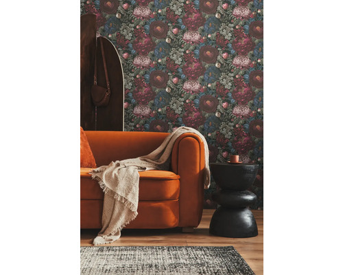 Woonkamer met bloemenbehang, bank en bijzettafel.
