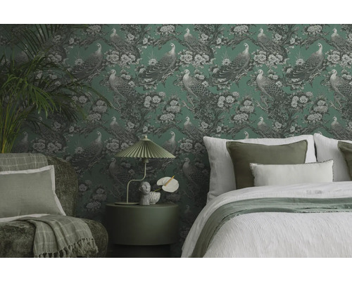 Decoratieve slaapkamer met behang met motief, bed, fauteuil en bijzettafel